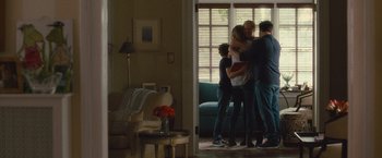 Movie still from “Trainwreck” (2015), directed by Judd Apatow – A group of people standing in a living room hugging; Wide shot, Over the shoulder angle