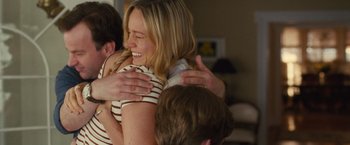 Movie still from “Trainwreck” (2015), directed by Judd Apatow – A woman is hugging a man in a room with other people; Medium shot, Over the shoulder angle
