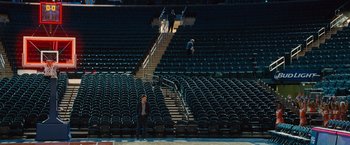 Movie still from “Trainwreck” (2015), directed by Judd Apatow – A man standing in an empty stadium with stairs and seats; Extreme Wide shot, High angle