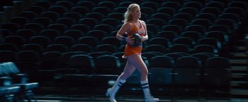 Movie still from “Trainwreck” (2015), directed by Judd Apatow – A woman is walking through a stadium holding a ball; Wide shot, Low angle