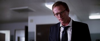 Movie still from “Transcendence” (2014), directed by Wally Pfister – A man in a suit and tie standing in front of a wall; Close Up shot, Over the shoulder angle