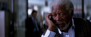 Movie still from “Transcendence” (2014), directed by Wally Pfister – An older man talking on a cell phone while wearing a suit; Close Up shot, High angle