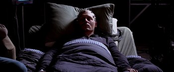 Movie still from “Transcendence” (2014), directed by Wally Pfister – A man laying in a bed with pillows on the floor; Medium shot, Overhead angle