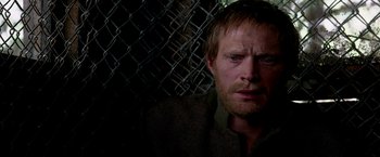 Movie still from “Transcendence” (2014), directed by Wally Pfister – A person with a chain link fence in the background; Close Up shot, High angle