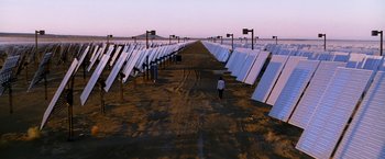 Movie still from “Transcendence” (2014), directed by Wally Pfister – People walk down a dirt road in front of a field of solar panels; Extreme Wide shot, High angle