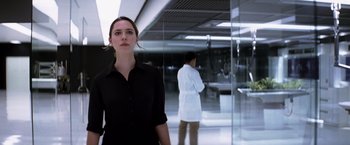 Movie still from “Transcendence” (2014), directed by Wally Pfister – A woman standing in front of a man wearing a lab coat; Medium shot, Low angle
