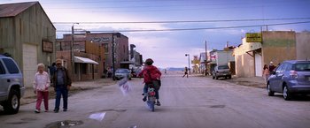 Movie still from “Transcendence” (2014), directed by Wally Pfister – A person riding a bike down the middle of a street; Extreme Wide shot, High angle
