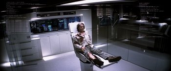 Movie still from “Transcendence” (2014), directed by Wally Pfister – A man sitting on a chair in a room; Wide shot, High angle