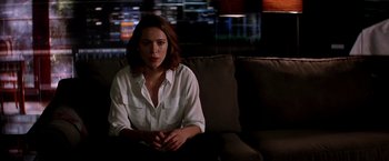 Movie still from “Transcendence” (2014), directed by Wally Pfister – A woman sitting on top of a couch in a living room; Medium shot, Over the shoulder angle