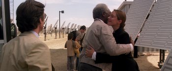 Movie still from “Transcendence” (2014), directed by Wally Pfister – A man and a woman hugging in front of a group of people; Medium shot, Over the shoulder angle