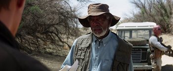 Movie still from “Transcendence” (2014), directed by Wally Pfister – An older man wearing a hat while holding papers; Medium shot, Over the shoulder angle