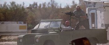 Movie still from “Transcendence” (2014), directed by Wally Pfister – A man riding in the back of an army vehicle; Wide shot, Low angle