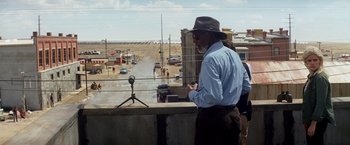 Movie still from “Transcendence” (2014), directed by Wally Pfister – An older man standing on the side of a road; Wide shot, Over the shoulder angle