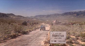 Movie still from “Tremors” (1990), directed by Ron Underwood – A car driving down a dirt road in the middle of the desert; Extreme Wide shot, Low angle