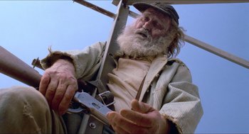 Movie still from “Tremors” (1990), directed by Ron Underwood – An old man holding a pair of scissors in his hands; Medium shot, Low angle
