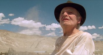 Movie still from “Tremors” (1990), directed by Ron Underwood – An older woman wearing a brown hat in the desert; Close Up shot, Low angle
