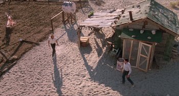 Movie still from “Tremors” (1990), directed by Ron Underwood – Two men are playing a game on the beach; Extreme Wide shot, High angle