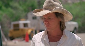 Movie still from “Tremors” (1990), directed by Ron Underwood – A man wearing a cowboy hat looking to his left; Close Up shot, Low angle
