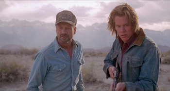 Movie still from “Tremors” (1990), directed by Ron Underwood – A man and a boy standing next to each other in the desert; Medium shot, Low angle