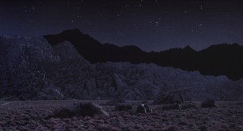 Movie still from “Tremors” (1990), directed by Ron Underwood – A night sky with a mountain range in the background; Extreme Wide shot, High angle