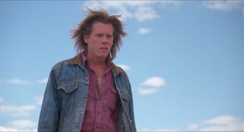 Movie still from “Tremors” (1990), directed by Ron Underwood – A man standing in front of a blue sky; Close Up shot, Low angle