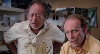 Movie still from “Tremors” (1990), directed by Ron Underwood – Two men are standing next to each other in a kitchen; Close Up shot, Low angle