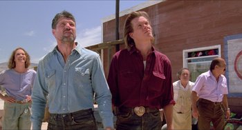 Movie still from “Tremors” (1990), directed by Ron Underwood – A man and a woman standing next to each other on a street; Medium shot, Low angle