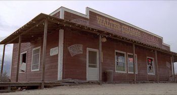 Movie still from “Tremors” (1990), directed by Ron Underwood – An old western style building with a sign on the side; Extreme Wide shot, Low angle