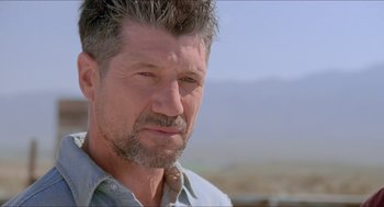 Movie still from “Tremors” (1990), directed by Ron Underwood – A person wearing a shirt and tie; Close Up shot, Over the shoulder angle