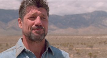 Movie still from “Tremors” (1990), directed by Ron Underwood – A person wearing a blue shirt; Close Up shot, Low angle