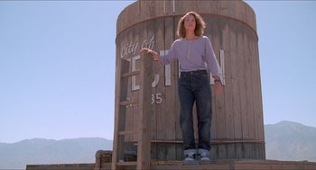 Movie still from “Tremors” (1990), directed by Ron Underwood – A woman standing in front of a water tower; Wide shot, Low angle