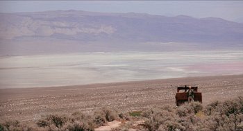 Movie still from “Tremors” (1990), directed by Ron Underwood – An old truck is parked on the side of the road; Extreme Wide shot, High angle