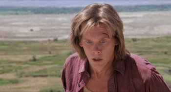 Movie still from “Tremors” (1990), directed by Ron Underwood – A man with long hair and blue eyes stares at the camera; Close Up shot, Low angle