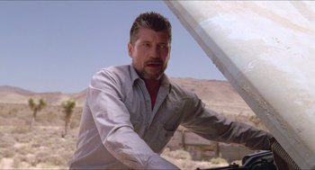 Movie still from “Tremors” (1990), directed by Ron Underwood – A person riding a bike on a dirt road; Medium shot, Low angle