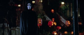 Movie still from “Trick 'r Treat” (2007), directed by Michael Dougherty – A person wearing a mask and a black hooded jacket; Medium shot, Low angle