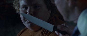 Movie still from “Trick 'r Treat” (2007), directed by Michael Dougherty – A person holding a knife in front of their face; Close Up shot, Overhead angle