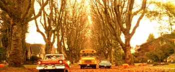 Movie still from “Trick 'r Treat” (2007), directed by Michael Dougherty – A school bus parked in the middle of a tree lined street; Extreme Wide shot, High angle