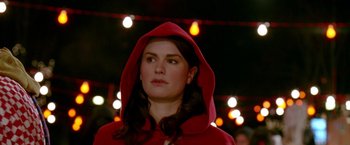 Movie still from “Trick 'r Treat” (2007), directed by Michael Dougherty – A woman wearing a red hooded jacket in front of lights; Close Up shot, Over the shoulder angle