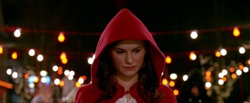 Movie still from “Trick 'r Treat” (2007), directed by Michael Dougherty – A woman wearing a red hooded cape in front of lights; Close Up shot, High angle