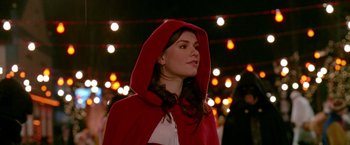 Movie still from “Trick 'r Treat” (2007), directed by Michael Dougherty – A woman wearing a red hooded cape standing in front of lights; Close Up shot, Over the shoulder angle