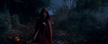 Movie still from “Trick 'r Treat” (2007), directed by Michael Dougherty – A woman wearing a red cape walking through the woods; Wide shot, High angle