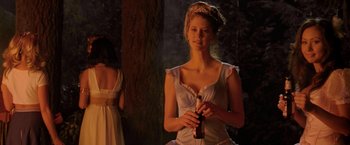 Movie still from “Trick 'r Treat” (2007), directed by Michael Dougherty – A beautiful young lady holding a bottle of beer in her hands; Medium shot, Over the shoulder angle