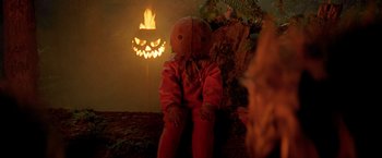 Movie still from “Trick 'r Treat” (2007), directed by Michael Dougherty – A creepy looking doll sitting in front of a lit pumpkin; Medium shot, Low angle
