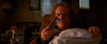 Movie still from “Trick 'r Treat” (2007), directed by Michael Dougherty – An older man with a beard and mustache is holding a cell phone; Close Up shot, Low angle