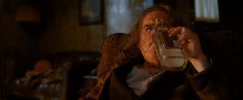Movie still from “Trick 'r Treat” (2007), directed by Michael Dougherty – An older man sitting in a chair holding a bottle; Close Up shot, High angle