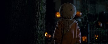 Movie still from “Trick 'r Treat” (2007), directed by Michael Dougherty – A person with a mask is standing next to a tree; Medium shot, Low angle