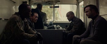 Movie still from “Triple 9” (2016), directed by John Hillcoat – Two men are sitting on a bus together; Medium shot, Over the shoulder angle
