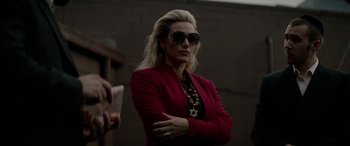Movie still from “Triple 9” (2016), directed by John Hillcoat – A woman wearing a red jacket and sunglasses; Medium shot, Over the shoulder angle