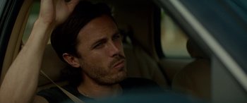 Movie still from “Triple 9” (2016), directed by John Hillcoat – A person sitting in a car; Close Up shot, Over the shoulder angle
