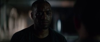 Movie still from “Triple 9” (2016), directed by John Hillcoat – A person wearing a black t - shirt; Close Up shot, Over the shoulder angle